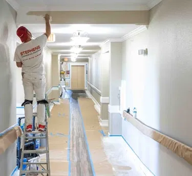 A professional painter carefully finishing a commercial hallway